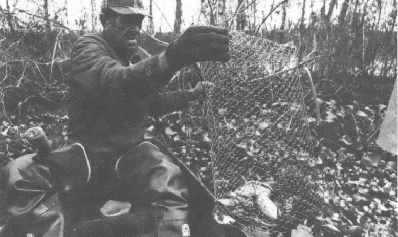 Black and white photo of Black man in cap emptying out fishing nets