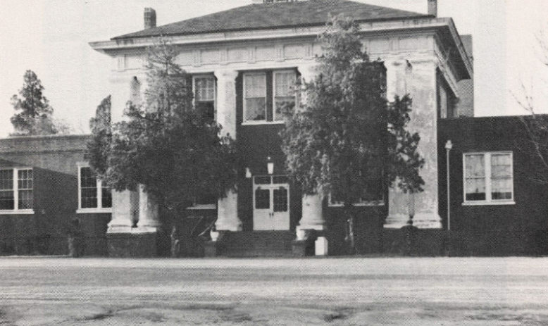Black and white photo of building with imposing columns and trees in front