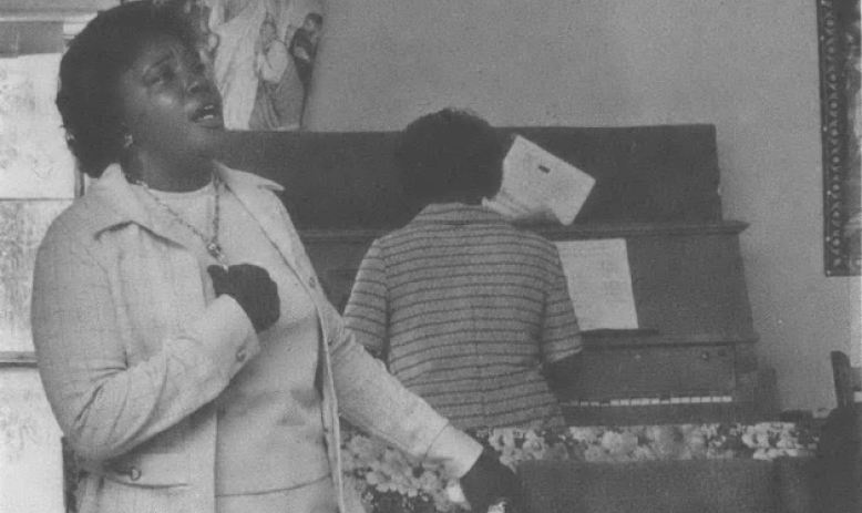 Black woman singing as another woman plays the piano