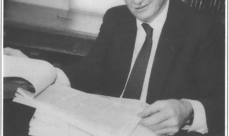 Older man in suit and tie reading documents 
