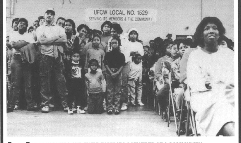 Delta Pride workers and their families at a community center sitting and standing in an auditorium a sign on the wall reads "UFCW Local No. 1529 Serving its Members & the Community"