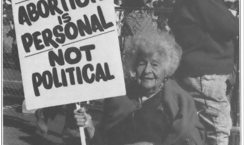 woman holding sign reading "Abortion is personal, not political"