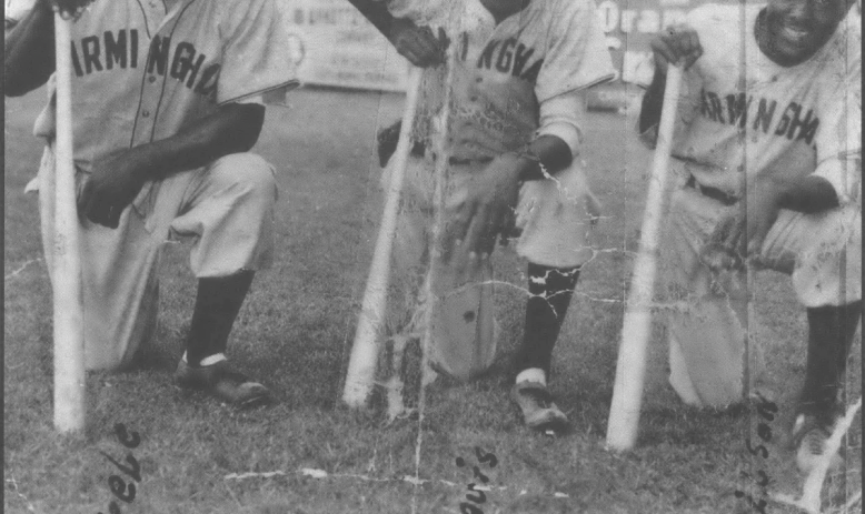 Old photo of three Black baseball players in uniform kneeling with bats