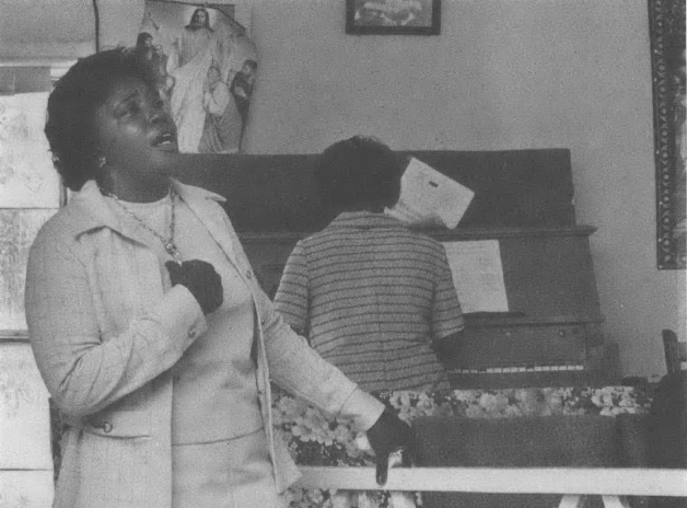 Black woman singing as another woman plays the piano