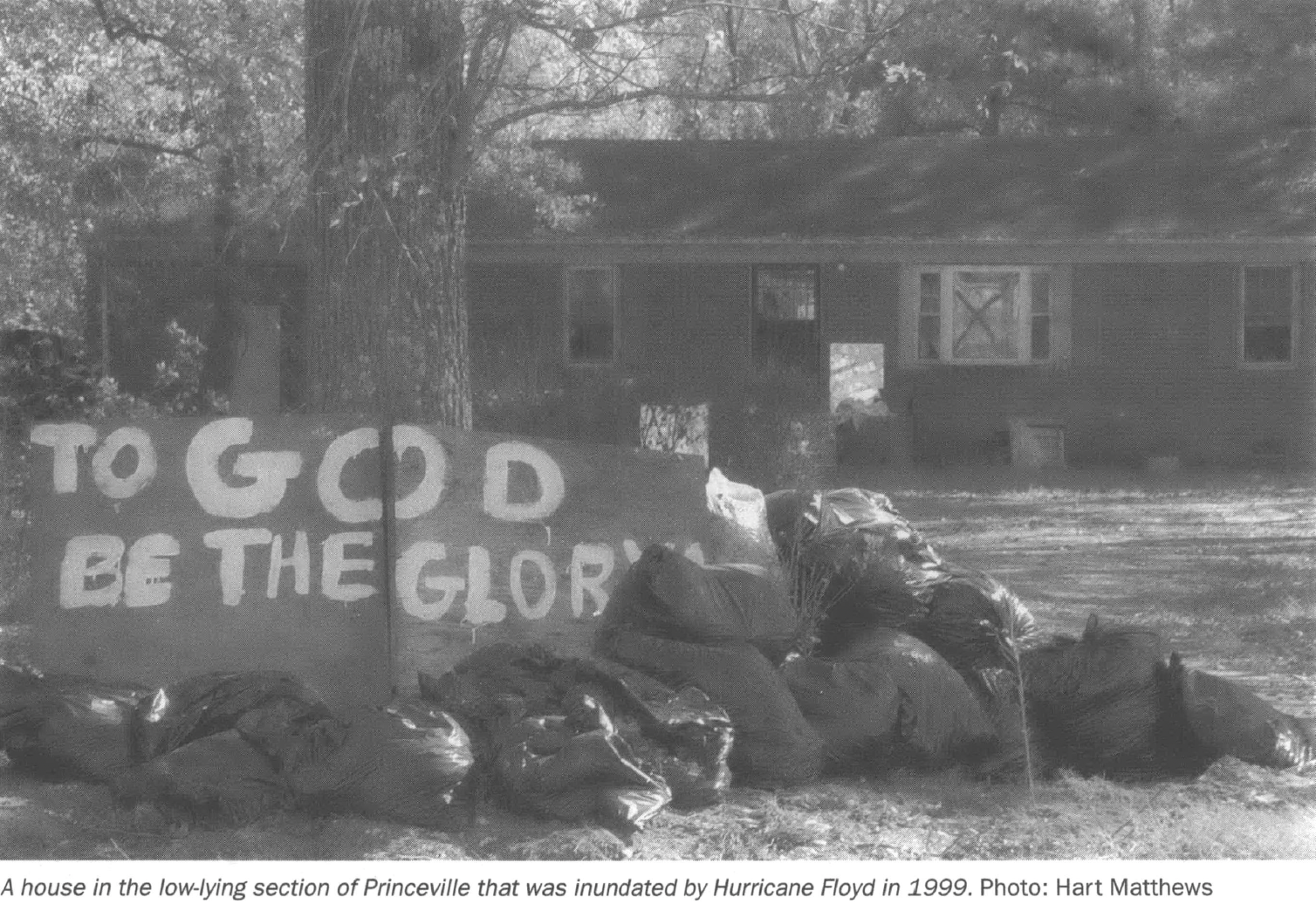 Spray painted sign on plywood reading To God Be the Glory