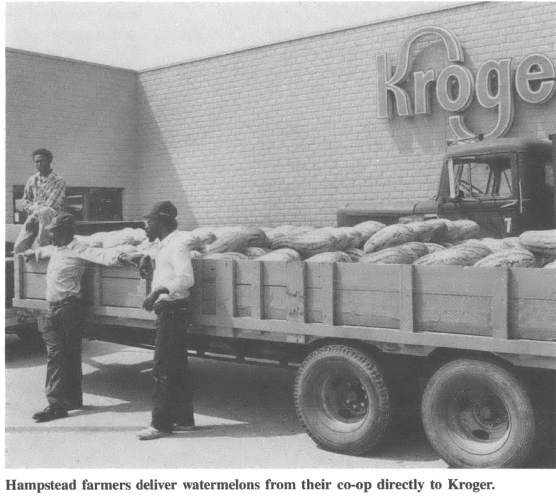 People stand in front of a tractor trailer pallet in front of Kroger