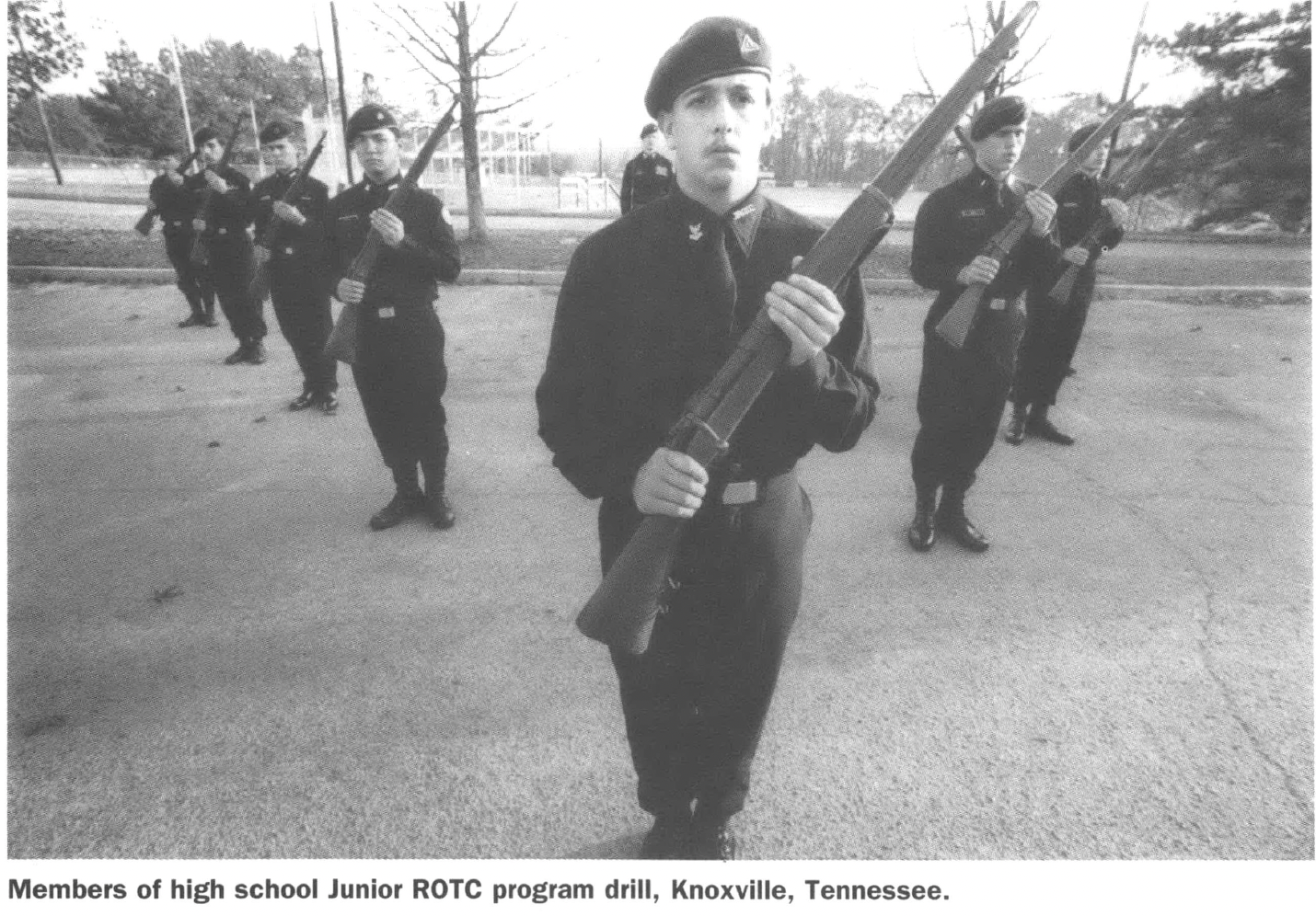Children in military formation holding guns