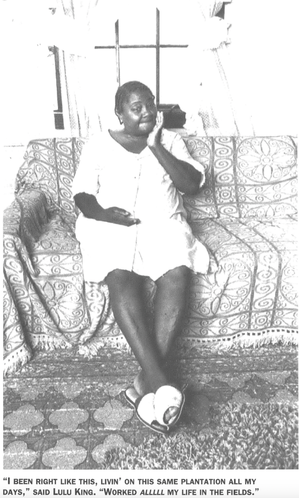 Black woman in dress sitting on a sofa in the home