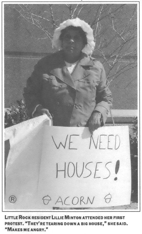 woman in a winter coat standing infront of a building with a sign that reads "We Need Houses! ACORN"
