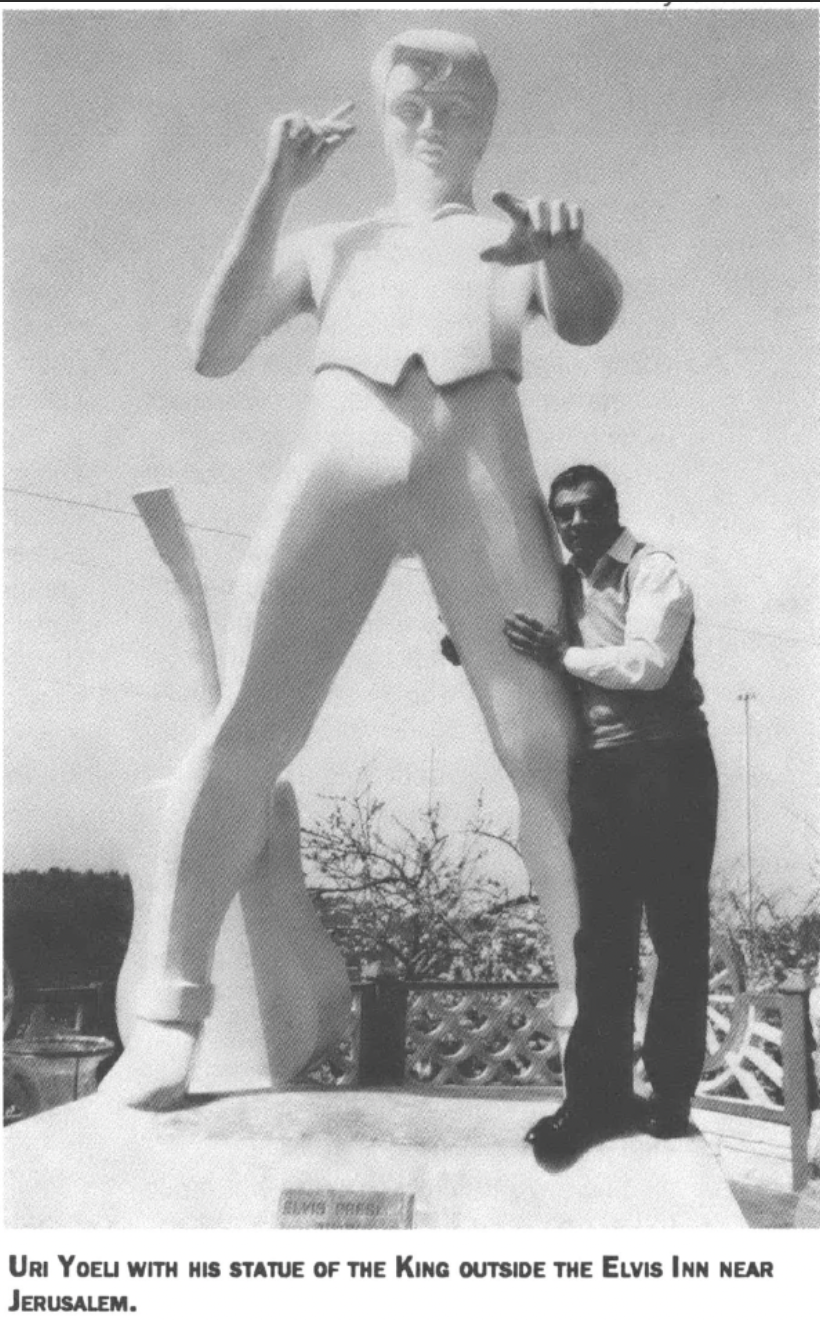 man poses with Elvis Presley statue