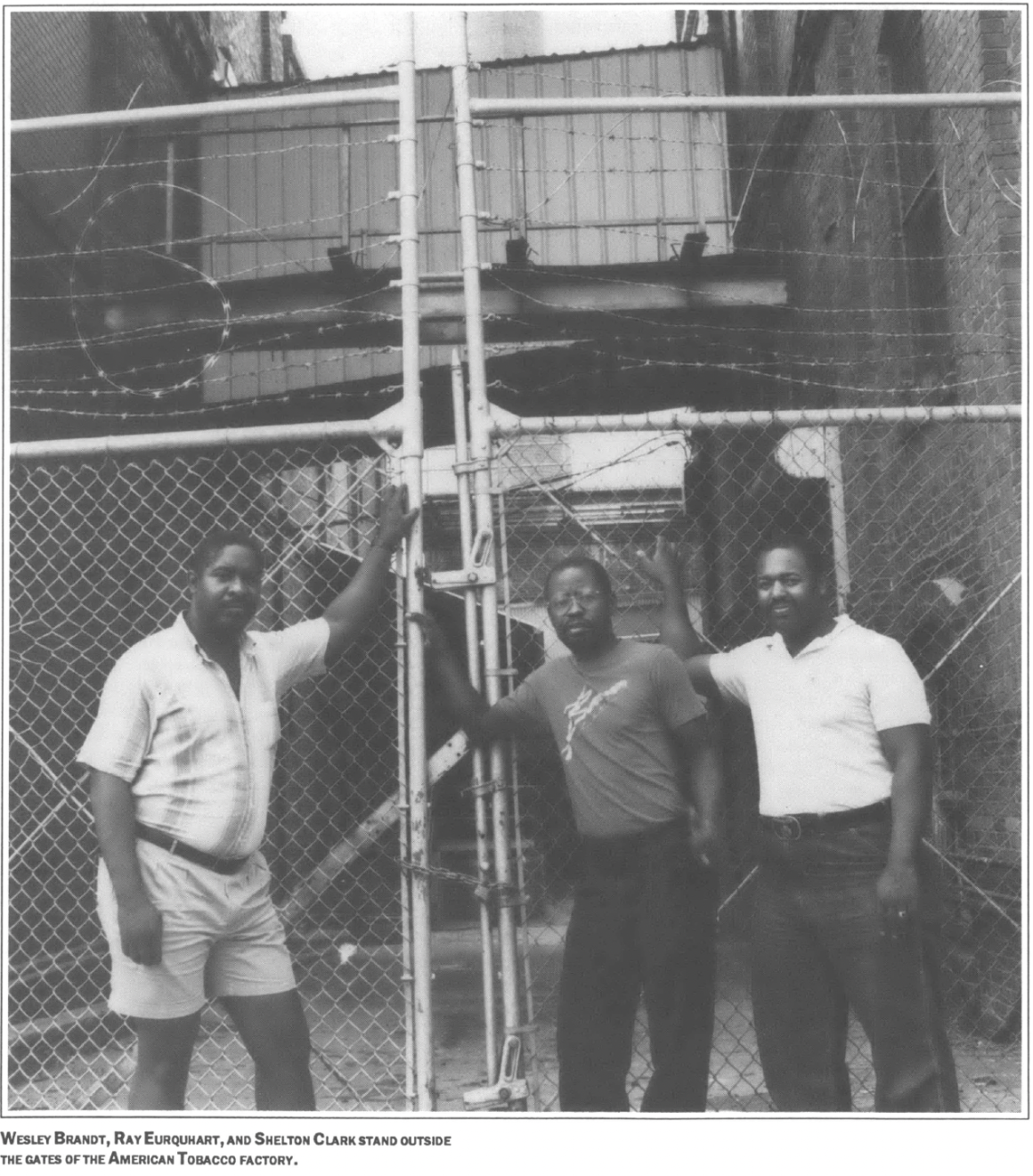 three men stand outside the gates of the American Tobacco factory