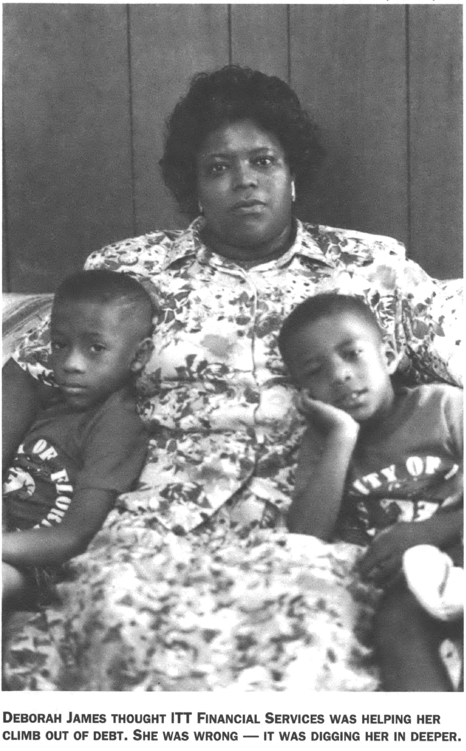 Black woman in floral dress seated holding two young children