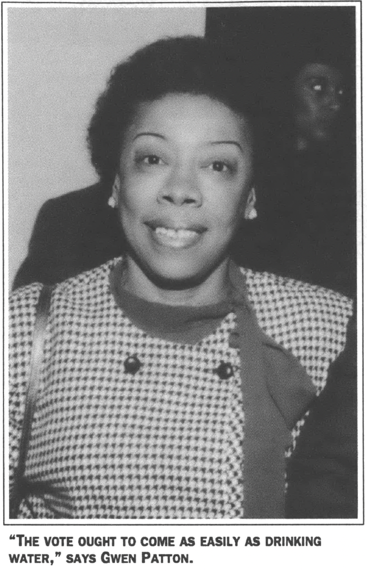 Portrait of Black woman in gingham dress and short hair smiling at the camera 