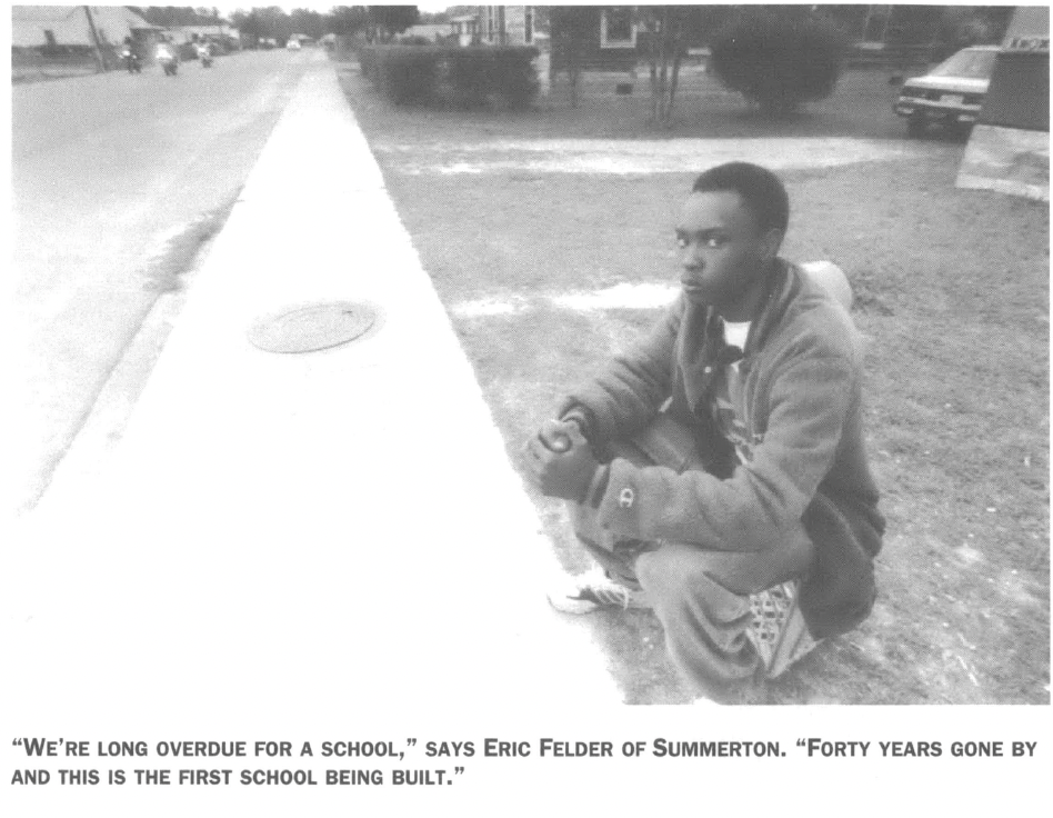 Black teenager kneeling by sidewalk 