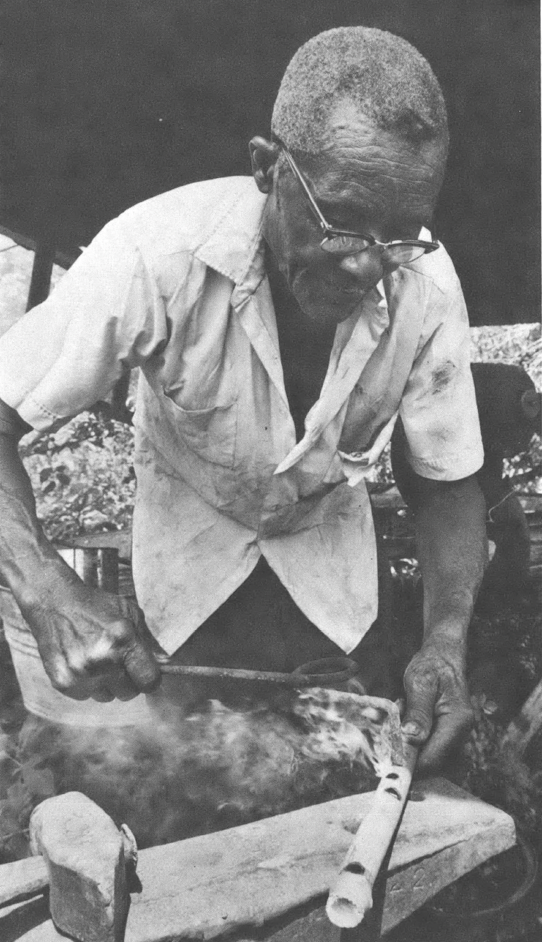 Black and white photo of Black man in white shirt leaning over a table